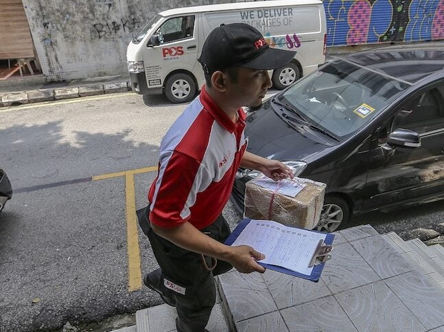 Seorang pekerja Pos Malaysia sedang bertugas. - Foto ihsan Malay Mail