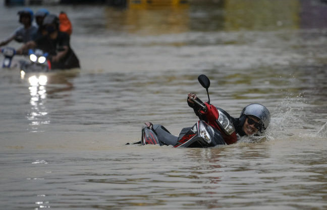 Seorang penunggang motosikal terjatuh ketika meredah banjir di Selangor. - Foto ihsan Bernama